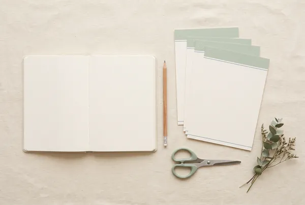 An open notebook and pencil arranged on a cream linen surface